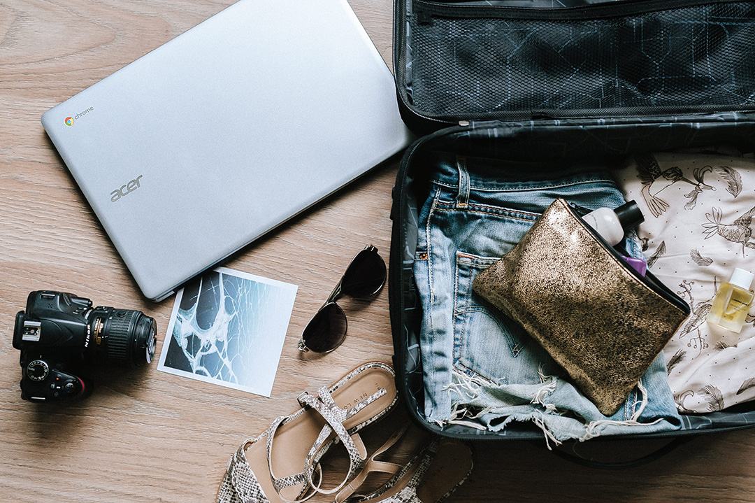 Packing a suitcase with clothes, shoes, camera and laptop.