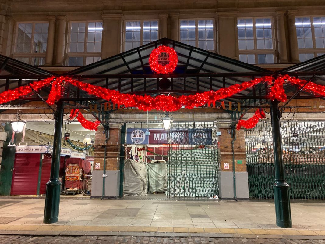 The outside of Covent Garden Christmas Market decorated with red Christmas lights