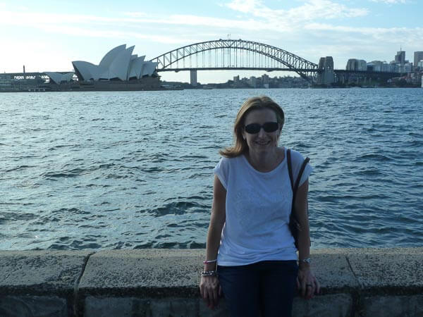 Emma sitting in front of Sydney Opera House and Harbour Bridge