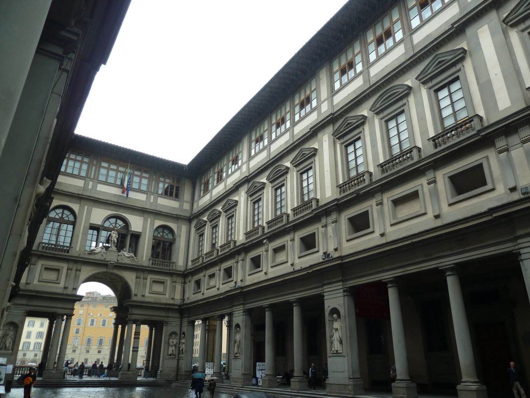 Looking up from the courtyard at the grey building of the Uffizi Gallery