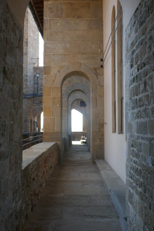View looking along corridor with stone floor and arches into the distance inside the Palazzo Vecchio