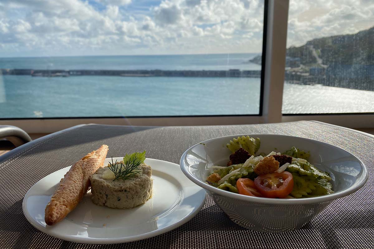 image of two plates of food resting on a sun lounger on the deck of a cruise ship overlooking the sea