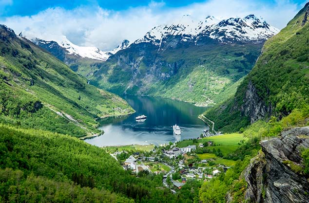 image of the view over Geirangerfjord. A channel of water surrounded by mountain