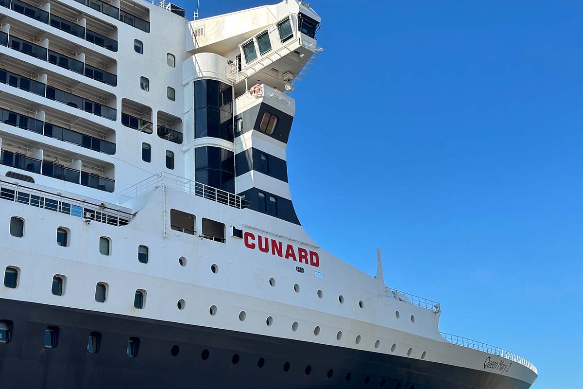 image of the front of the Cunard's Queen May 2 cruise ship. The hull is blue while the upper decks are white.