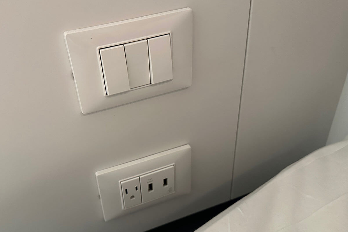 Plugs and USB ports on the wall next to the bed in a Solo Insider cabin on Virgin Voyages.