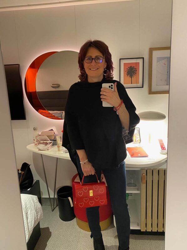 Emma of Emmaonline wearing a black poncho with a red bag for Scarlet Night on Virgin Voyages
